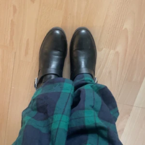 Svarta boots med spänne - Snygga svarta boots i skinn med ett dekorativt spänne på sidan. Perfekta för en stilren look och passar bra till både jeans och klänning.