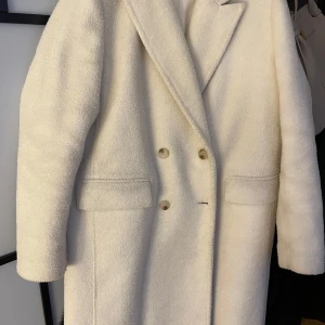 Beige teddyjacka - Säljer en mysig beige teddyjacka med dubbelknäppning och breda slag. Jackan har en klassisk design med fickor framtill och är perfekt för kyligare dagar. Har några fläckar som enkelt går att få bort därav priset. 