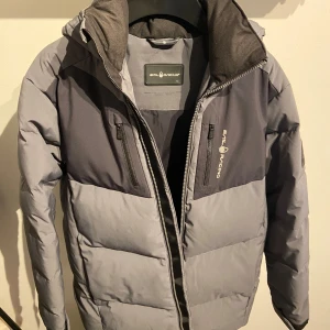Grå dunjacka från Sail Racing - Tja! Säljer nu min Sail racing dun jacka då den blivit för liten, endast använd en vecka i fjällen så väldigt sparsamt använd! Storlek 160 men passar upp till ca 170  Nypris 3199 