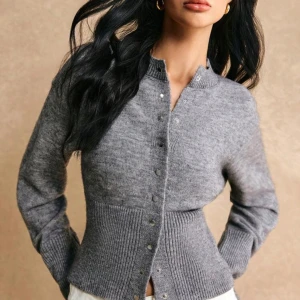 Grå stickad kofta med knappar - Säljer en stilren grå stickad kofta med knappar framtill. Koftan har en ribbad design vid ärmslut och nederkant, samt en tightare midja vilket ger en supersnygg passform. 💓 köpt på vinted i nyskick och använd av mig 1 gång🩷 storlek xs men passar även S😊