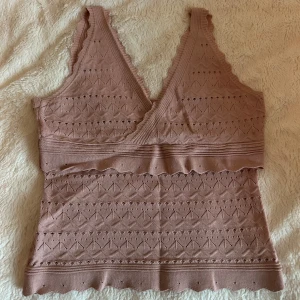 Rosa stickad topp från Vintage Dressing - Säljer en söt rosa stickad topp från Vintage Dressing med v-ringning och spetsdetaljer. Toppen är i storlek S och har ett fint mönster och är perfekt för varmare dagar. Den är ärmlös och har en bekväm passform. Knappt använd så skicket är superbra. 