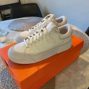 Vita sneakers från Nike - Snygga vita sneakers från Nike med en stilren design. Skorna är knappt använda och är i ett väldigt bra skick. Normal i storlek.