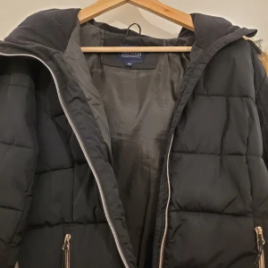 Svart pufferjacka från Race Marine - Säljer en svart pufferjacka från Race Marine med päls på luvan. Jackan har en dragkedja framtill och dragkedjor på ärmarna. Köpt för ca 2 år sen men knappt använd då den är lite för stor för mig.