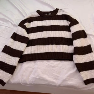 Randig brun och vit tröja från H&M - Säljer en snygg randig tröja i brunt och vitt. Tröjan är croppad med långa ärmar och har en ribbad kant vid halsen. Perfekt för en avslappnad stil!