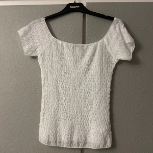 Vit topp från Zara - Säljer en snygg vit topp från Zara i storlek S. Den har en vågig textur och korta ärmar, perfekt för sommardagar. Toppen är i mycket bra skick och passar både till vardags och fest. Tillverkad i Turkiet.
