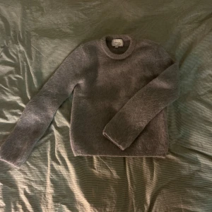 Grå mohairtröja från H&M Edition - Säljer en supermjuk och stilren grå mohairtröja från H&M Edition. Tröjan har en klassisk rund hals och långa ärmar, perfekt för kyliga dagar. Den är tillverkad i en blandning av mohair, ull och polyamid för extra komfort och värme.