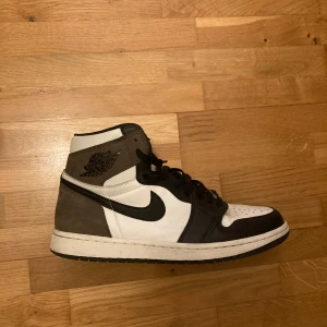 Nike Air Jordans 1 Mocha - Snygga Nike Air Jordans i en stilren kombination av svart, vitt och brunt som kallas ”Mocha”. Helt äkta köpta på sole story. Använda men i bra skick!