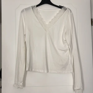 Vit långärmad topp med spetsdetaljer - En långärmad topp med spets i xs nästan aldrig använd