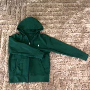  Polo Ralph Lauren Zip Hoodie - Snygg grön hoodie från Polo Ralph Lauren med dragkedja och klassisk logga på bröstet. Perfekt för en avslappnad stil med praktiska fickor och huva.