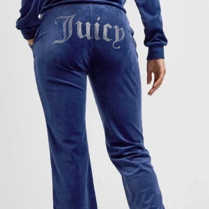 Blå velourbyxor från Juicy Couture - Snygga blå velourbyxor från Juicy Couture med glittrande detaljer. Byxorna har en bekväm passform och resår i midjan med snörning. Perfekta för en avslappnad stil med en touch av glamour. Har andvänt några gånger, men i fint skick.