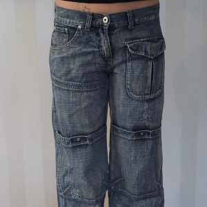 Grå cargopants från Karen-Kate - Säljer ett par grå cargopants från Karen-Kate i bra skick. Byxorna har flera fickor med knappar och en loose passform. Perfekta för en avslappnad stil. De är tillverkade i ett slitstarkt material och har en cool, vintage look. Lite slitna vid benslut, se sista bilden.
