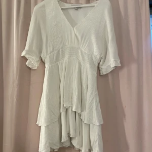 Vit klänning från new Yorker  - Använd en gång! Säljer en superfin vit klänning från new Yorker i storlek M. Den har en v-ringad design med korta ärmar och volangdetaljer. Klänningen är i mycket bra skick och har en luftig passform. Hör av dig för mer information💕
