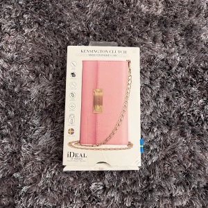 Rosa Kensington Clutch från iDeal of Sweden - Säljer en superfin rosa Kensington Clutch från iDeal of Sweden. Den är perfekt för att bära din mobil och har en snygg kedja i guld. Clutchen är i nytt skick och kommer i originalförpackning. Lägg märke till lite skadad förpackning men annars helt ny i sig! Kostar 300kr ny, går att pruta 