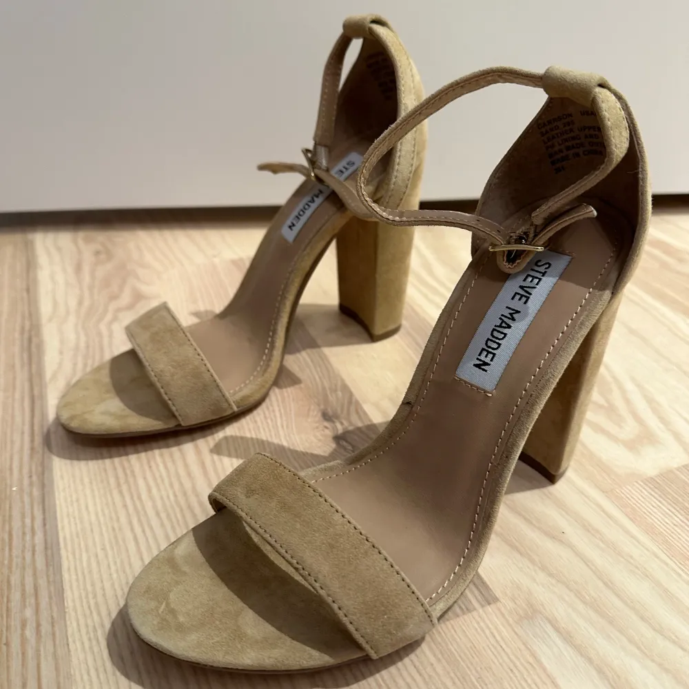 Snygga beige klackskor från Steve Madden i mocka. De har en bred klack och en elegant rem runt ankeln för extra stöd. Perfekta för att lyfta din stil till nästa nivå. Str 36 aldrig använda . Kengät.
