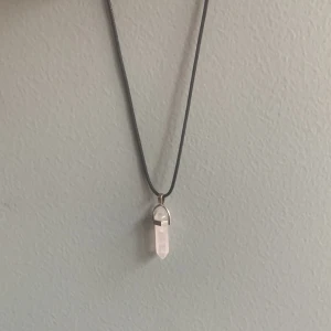 Halsband med vit kristallhänge - Snyggt halsband med ett vitt kristallhänge. Hänget är spetsigt och infattat i en silverfärgad hållare. Har bara använt en gång så är i nyskick🩷Köpte för ca 75kr. Ca 40 cm långt. Köparen står för frakt💖