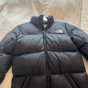 Svart dunjacka från The North Face - Säljer en snygg och varm svart dunjacka från The North Face perfekt för vintern i storlek S men kan också passa som XS. Säljer då jag har för många jackor. Super fint skick då den är använd typ 3 gånger. Orginal pris 3599. 