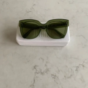 Gröna/Kiwi solglasögon från Chimi - Snygga gröna/Kiwi solglasögon från Chimi i ett coolt, transparent material. De har en modern, fyrkantig form som ger en trendig look. Kommer med ett stilrent vitt fodral. Solglasögonen är i nyckick och fick aldrig användning, därför säljer jag de.