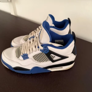 Air Jordan 4 Retro Motorsports - Säljer ett par klassiska Nike Air Jordans i vitt och blått. Skorna har en snygg design med snörning och är i bra skick. Perfekta för både vardag och fest! 🏀Nypris: 14 000. Modellen heter Air Jordan 4 Retro Motorsports. Strl 44.5