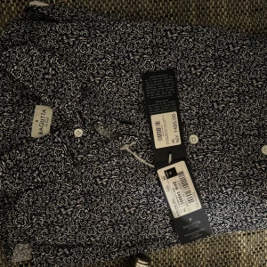 Helt ny Svartvit mönstrad skjorta från Bagutta - Snygg skjorta från Bagutta med ett unikt svartvitt mönster. Skjortan har knappar framtill och är perfekt för en stilren look. Passar bra till både vardag och speciella tillfällen.