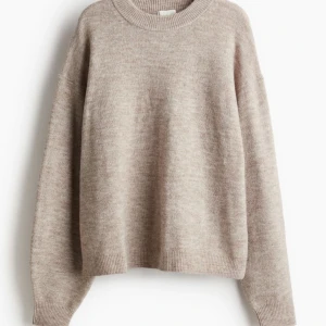Beige stickad tröja - Mysig beige stickad tröja med rund hals och långa ärmar. Perfekt för kyliga dagar och enkel att matcha med olika outfits. Bara fråga om de skulle vara något mer.