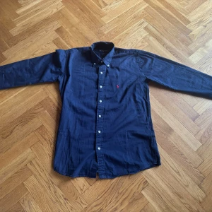 Mörkblå skjorta från Ralph Lauren - Säljer en snygg mörkblå skjorta från Ralph Lauren i storlek M. Skjortan är i 100% bomull. Jätte snygg till vardagen, passar bra med allt!