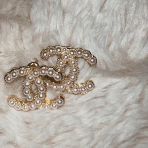 Guldörhängen med pärlor - Säljer ett par eleganta guldörhängen med pärlor. De har en klassisk design med dubbla C och är perfekta för att ge en lyxig touch till vilken outfit som helst. Passar både till vardag och fest. Örhängena är i mycket bra skick och redo att bäras av någon som älskar stil och elegans.