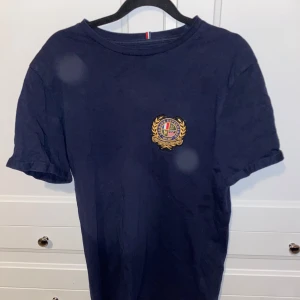 Mörkblå t-shirt från Les Deux - Snygg mörkblå t-shirt från Les Deux med ett stilrent emblem på bröstet. Perfekt för en avslappnad stil. T-shirten har korta ärmar och en klassisk rund halsringning.