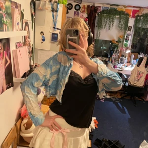 Blå och vit croppad skjorta från Bershka - Säljer en cool blå och vit croppad skjorta från Bershka. Skjortan har ett unikt batikmönster och långa ärmar. Perfekt för att ge din outfit en färgglad touch!