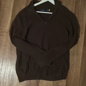 Brun halfzip från Polo Ralph Lauren - Säljer en snygg brun tröja från Polo Ralph Lauren i storlek L. Den har en dragkedja vid halsen och är perfekt för höst och vinter. Tröjan är långärmad och har en diskret logga på bröstet. Perfekt för en stilren och bekväm look!