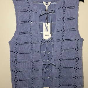 Ljuslila stickad väst från Object - Snygg ljuslila stickad väst från Object med knytning framtill. Västen har ett fint hålmönster och är perfekt för lager-på-lager-stil.