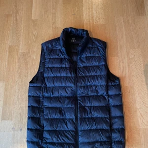 Uniqlo väst - Uniqlo väst i jätte bra skick, sparsamt använd. Går att väckla in i en påse. Den är mörkblå men ser svart ut på bild.                         Hör av er vid fler frågor! 