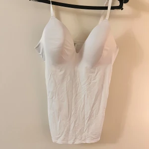 Vit linnetopp från Primark - Säljer en vit linnetopp från Primark med justerbara axelband. Toppen har en tight passform och är perfekt för lager-på-lager eller som den är. Enkel och stilren design.