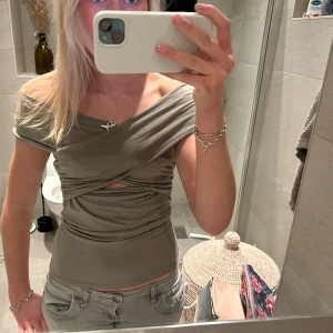 Grön offshoulder topp - Snygg grön offshoulder topp med knytdetalj framtill. Perfekt för en trendig look.