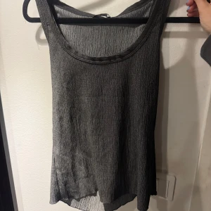 Grå ärmlös topp från Zara - Snygg grå ärmlös topp från Zara i ett lätt och luftigt material. Perfekt för varma dagar eller som ett lager under en jacka. Toppen har en enkel och stilren design som passar till många olika outfits.