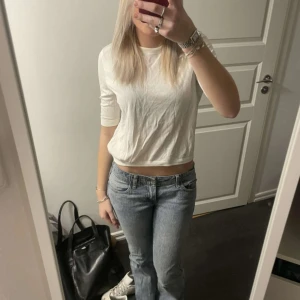 Vit topp med öppen rygg från COS - Säljer en vit topp från COS med en unik öppen ryggdetalj. Toppen har trekvartsärmar och en rund halsringning. Perfekt för en stilren och modern look.