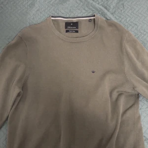 Olivgrön tröja från Junk de Luxe - Snygg olivgrön tröja från Junk de Luxe i ekologisk bomull. Den har en diskret broderad krona på bröstet och rund halsringning. Perfekt för en stilren look.