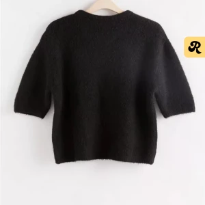 Stickad t shirt från Lindex - Snygg och enkel svart tröja från Lindex. Den har en rund halsringning och trekvartsärmar, perfekt för en stilren look. Passar bra till både jeans och kjol.