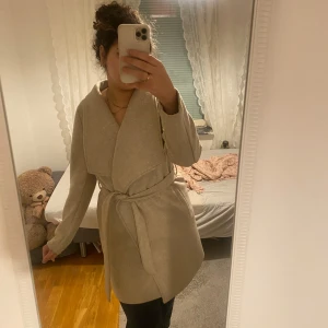 Beige kappa  - Säljer en ny beige kappa med knytband i midjan. Den är använd Max 2 gånger så den är i nytt skick ❤️