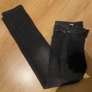 Jack & Jones jeans  - Snygga mörkgrå slim jeans från Jack & Jones. Perfekta för en stilren look med klassisk femficksdesign och dragkedja. Midjemått 28 och längd 30.