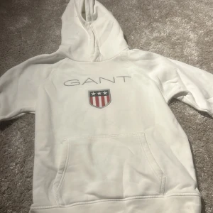 Vit hoodie från GANT - Säljer en vit hoodie från GANT. Knappt använd och hoodien är i storlek 146/152 cm i barnstorlek 