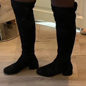 Svarta knähöga boots från K.cobler - Snygga svarta boots i mocka med låg klack från K.cobler! Strl 37, normala i storleken. De är använda men har inga skador.