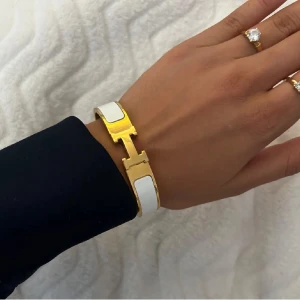 Vitt och Guldigt H armband - Så fint vitt armband med gulddetaljer och ett H-format spänne som tyvärr inte kommer till användning. Pris kan diskuteras💕✨