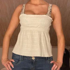 Vitt linne - Säljer ett sött vitg linne med smockad överdel. Perfekt för varma sommardagar. Linnet har en avslappnad passform och är tillverkat i ett lätt material.