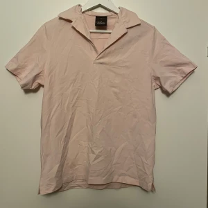 Oscar Jacobson piké  - Säljer en stilren ljusrosa kortärmad tröja från Oscar Jacobson. Tröjan har en klassisk krage och är perfekt för en avslappnad look. Passar bra till både jeans och chinos. Oanvänd utom när bilden togs. Nypris 1000kr