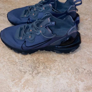 Nike Air Max sneakers i blått - Snygga Nike Air Max sneakers i en stilren blå färg med svarta detaljer. Skorna har en modern design med synlig Air Max-dämpning i hälen och snörning framtill. Perfekta för både träning och vardag.