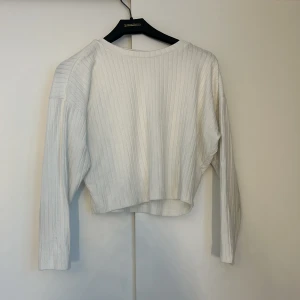 Vit ribbad tröja från H&M - Säljer en stilren vit ribbad tröja från H&M. Tröjan har en croppad passform och långa ärmar, perfekt för en avslappnad look. Passar bra till både jeans och kjol.