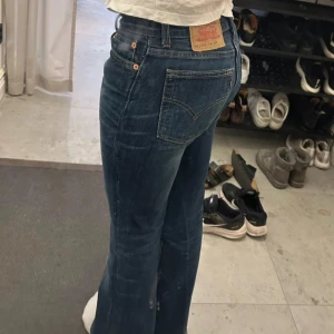 Levi's jeans i blå denim - Snygga Levi's jeans i blå denim med klassisk femficksdesign. De har en bootcut-stil och är perfekta för en avslappnad look. Märkeslappen på baksidan ger en autentisk touch.