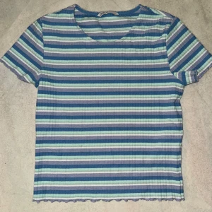 Randig topp från Only - Säljer en randig topp från Only i blå, grön och vit. Toppen har korta ärmar och en rund halsringning. 