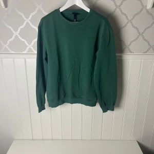 Grön tröja från H&M - Säljer en stilren grön tröja från H&M i storlek XS. Tröjan har en klassisk rund halsringning och långa ärmar. Perfekt för en avslappnad look.
