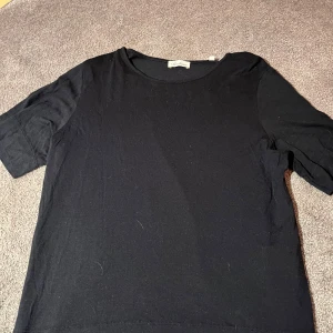 Svart topp från Stenströms - Säljer en stilren svart topp från Stenströms i storlek S. Toppen har korta ärmar och en klassisk rund halsringning. Perfekt för en enkel och elegant look.